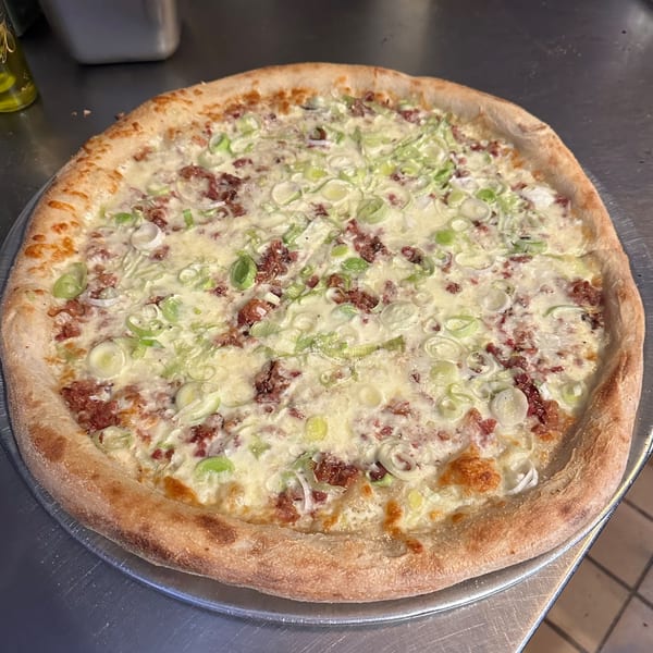 Mamma Mia's white pizza with sausage and scallions on a metal tray.