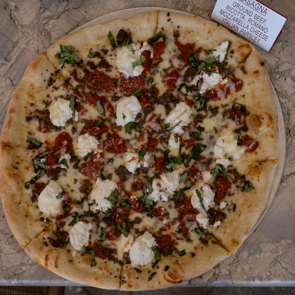 Mamma Mia's Lasagna pizza with ground beef, ricotta, mozzarella, Romano cheese, and fresh basil.